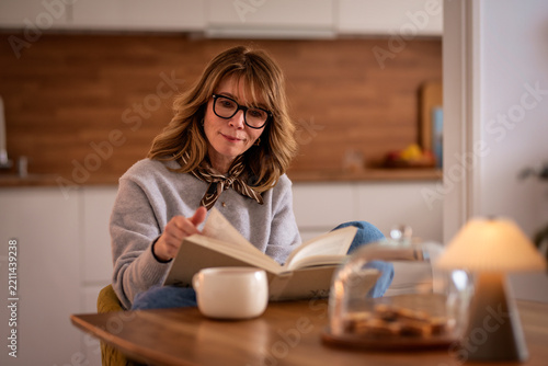 Confident woman with a book sitting at a table and reading