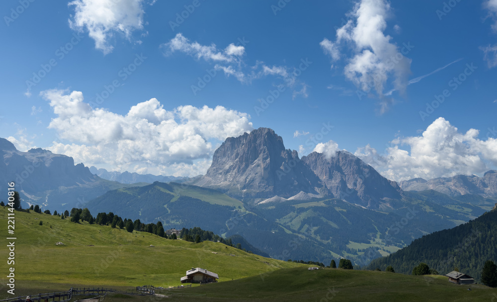 Obraz premium View of beautiful landscape in the Alps with fresh green meadows and mountain tops in the background on a sunny day with blue sky and clouds in summertime. Alpe di Cisles, Seceda Ridgeline, Dolomiti ,