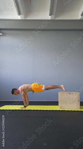 Muscular man performs decline push-ups with feet elevated on a plyo box. Upper body strength, chest training, calisthenics and bodyweight fitness concepts. Vertical video.