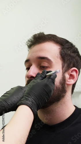 Plastic surgeon marking man's face before rhinoplasty procedure
