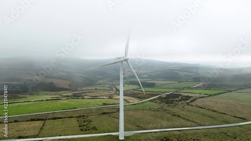 Wind turbine blades spinning on a foggy day generating renewable energy