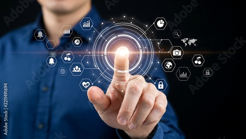 Man's finger touching glowing digital network with technology icons on dark background during innovation concept