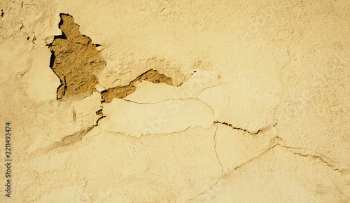 Fotografie Texture background with peeling yellow plaster on a wall and a patch of exposed
