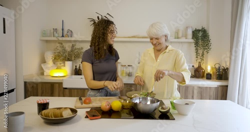 Happy mother and daughter taking a selfie with a smartphone while preparing a healthy salad at home