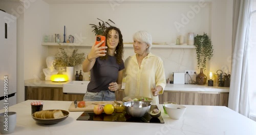 Grandmother and granddaughter preparing a healthy salad together in a modern kitchen