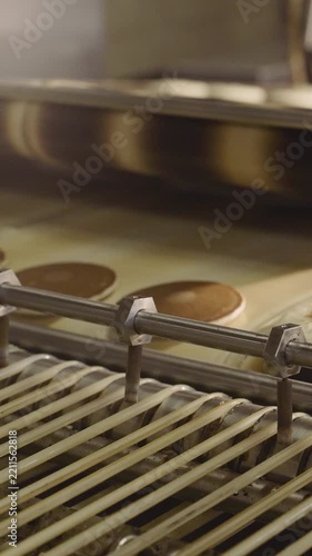 Close up of pancakes on an industrial conveyor belt. Automated machinery with sensors monitors food as it moves through a factory production line. Food manufacturing and mass production process
