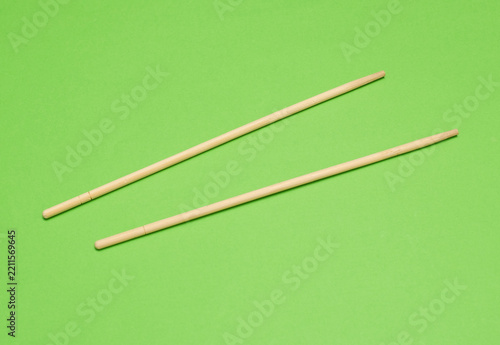 Pair of wooden bamboo chopsticks on green background