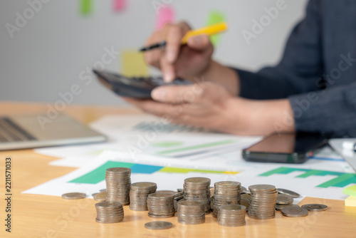 A close up shot of a man using a calculator to manage his monthly financial expenses and personal budget at a desk.