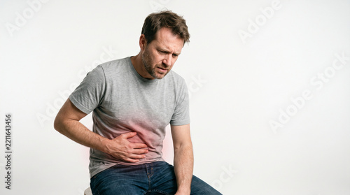 Man holding his abdomen with a pained expression, symbolizing stomach ache or digestive discomfort, representative of health issues