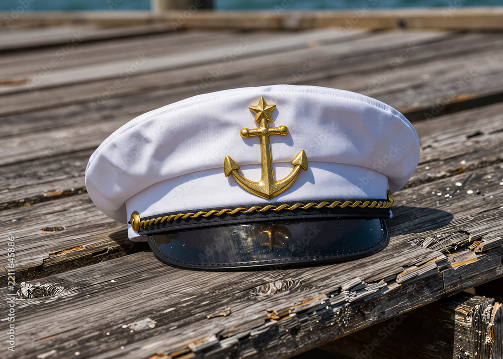 Obraz premium A white cap with a golden anchor and star lies on a dilapidated wooden pier