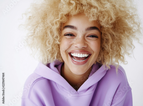 Smiling young woman with curly blonde hair wearing a purple hoodie