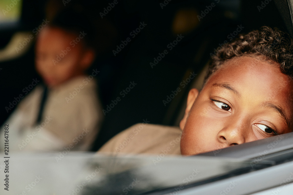 © Maskot - Contemplative boy leaning near car window during road trip