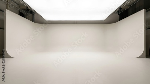 Empty white photography studio with a curved wall background and large overhead softbox lighting for professional shoots
