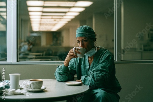 Healthcare worker in surgical scrubs drinking coffee during break