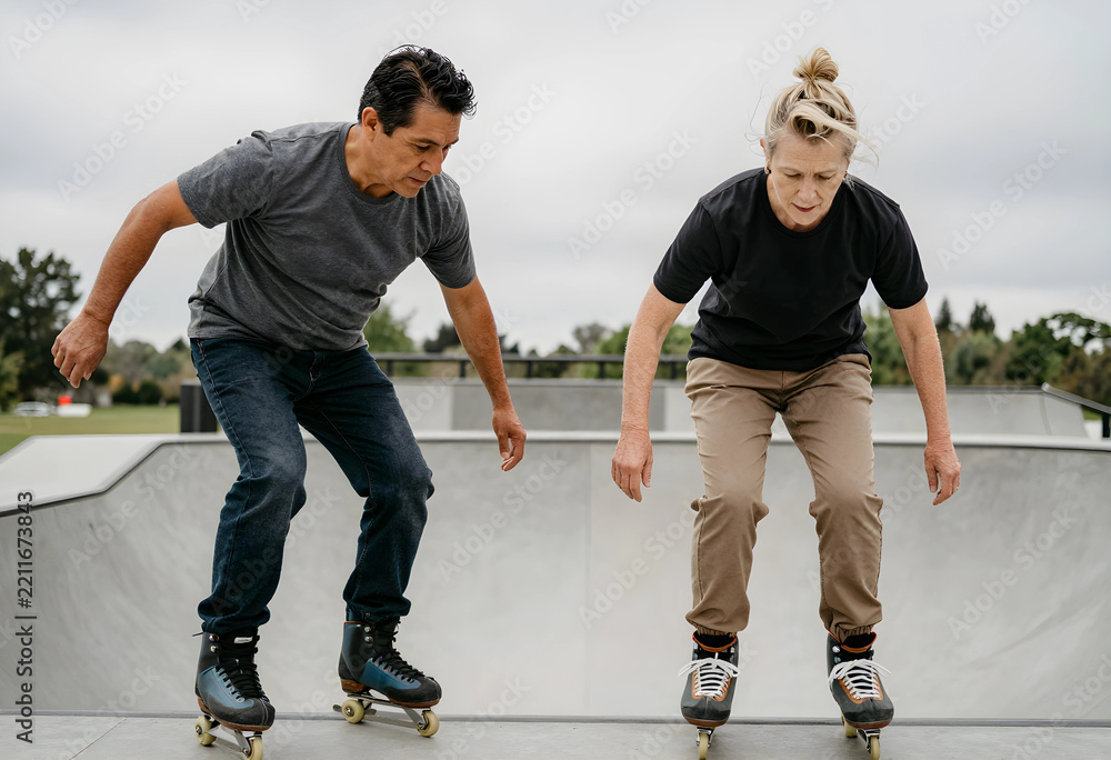 Fototapeta premium Active aging and healthy lifestyle, mature couple roller skating at a skate park to maintain physical fitness and mobility in their senior years