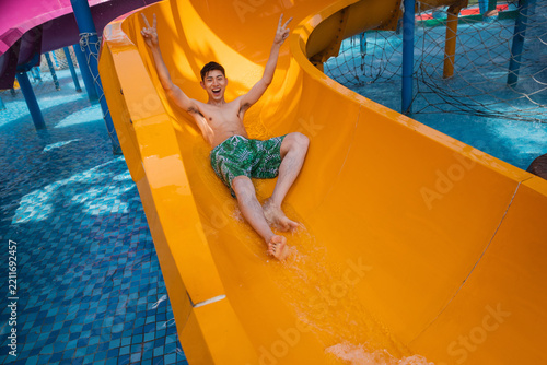 Obraz na plátně Young man enjoying waterslide ride at water park