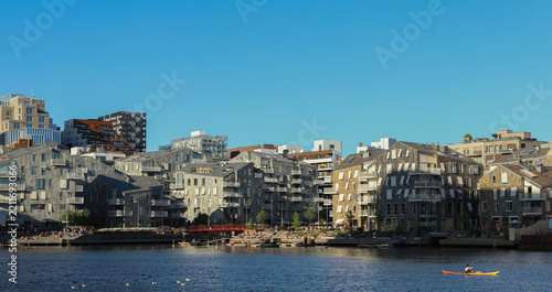 Modern architectural development and urban lifestyle in the capital city of Norway. Person kayaking in front of the modern Vannkunsten residential complex in Oslo, Norway.