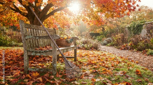 Wooden garden bench with metal rake in autumn park