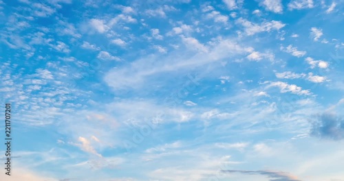 Beautiful time lapse of blue sky with white cumulus and cirrus clouds moving at sunset