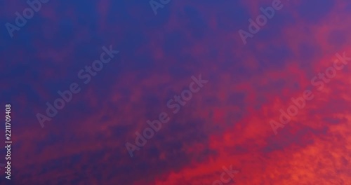 Beautiful dramatic time lapse of fiery red and orange sunset clouds moving fast across blue sky