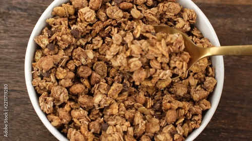 Chocolate granola scoop with spoon from bowl, close up