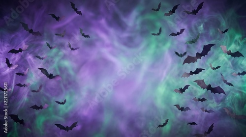 Spooky black bats flying in a swirling purple and green smoky Halloween background