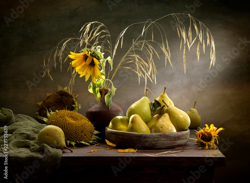 Still life with pears and sunflowers against a dark background