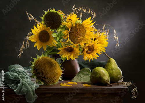 Still life with pears and a bouquet of sunflowers against a dark background
