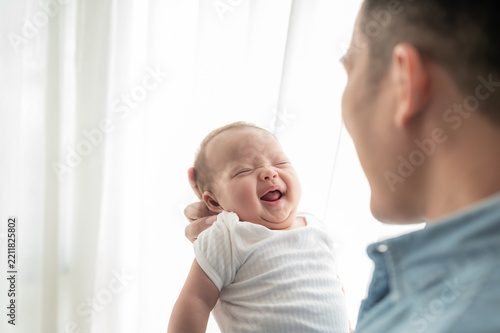 Happy Newborn Baby Being Held by Loving Father at Home