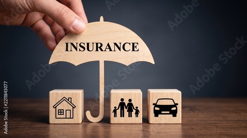 Insurance concept with wooden blocks protecting family, house, and car under umbrella