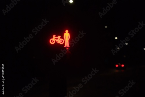 red stop sign on a pedestrian crossing with car tail lights in the distance at night 
