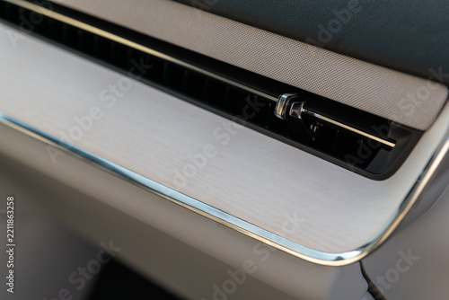 Modern car interior dashboard detail featuring light wood trim and sleek air vent ventilation