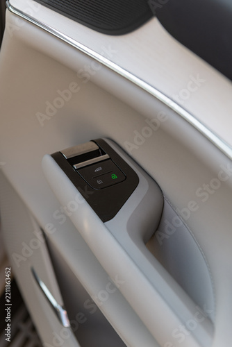Modern car door interior panel with electronic window switch and illuminated lock controls