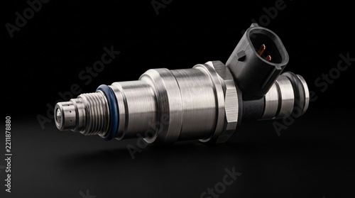 A metallic fuel injector isolated on a dark background for automotive engine component maintenance tasks with isolated solid manufacturing craftsmanship automobilia