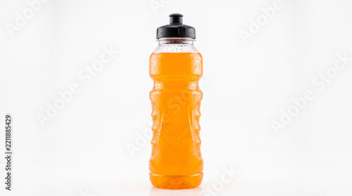A clear plastic sports water bottle filled with orange liquid against a plain white background with containing orange fluid stands upright against translucent sports