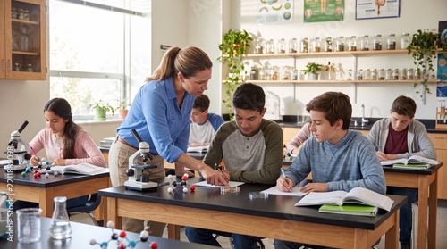 Female Science Teacher Guiding Students Through Hands On STEM Experiment In Modern Classroom