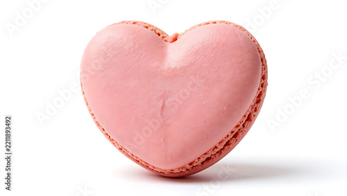 A single pink heart-shaped macaron sits invitingly on a white surface.