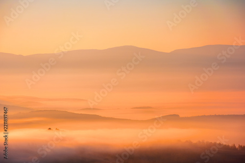 cold morning fog with red hot sunrise in the Carpathian mountains. rural valley of Perechyn district in morning mist. nature background with fog rolling over hillls