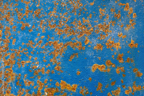 Close-up of a vivid blue painted metal surface covered with scattered orange rust, creating a weathered industrial texture.