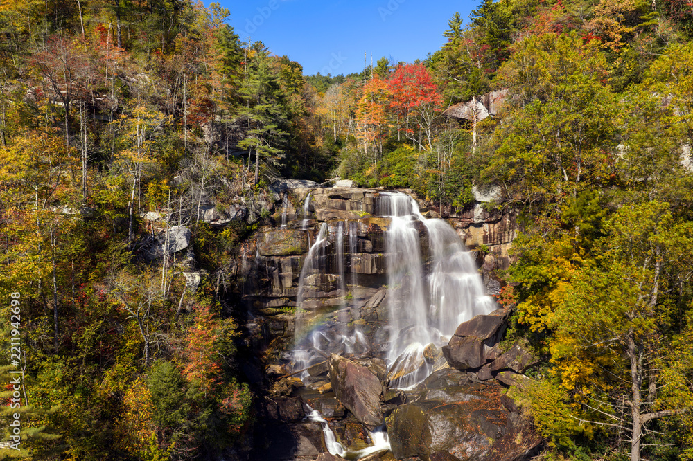 Obraz premium Beautiful waterfall landscape. Autumn view of Whitewater Falls. Water flows through colorful forest in Nantahala National Forest.