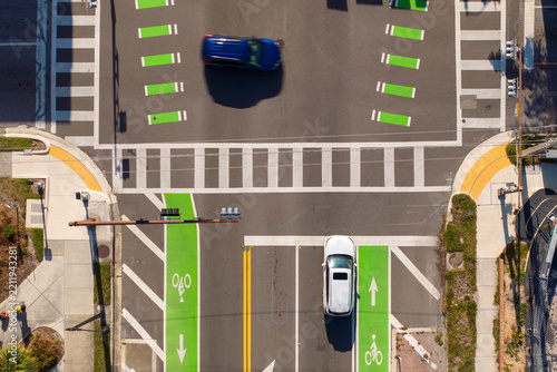 Dynamic street scene in Sarasota with people walking across a pedestrian crossing while traffic lights control the flow of vehicles at a busy junction.
