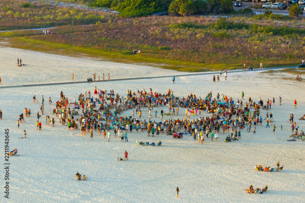 Obraz premium Large group of people gathered in a circle dancing and having fun on sandy beach at sea shore during summer vacations. Outdoor activities during travel time.