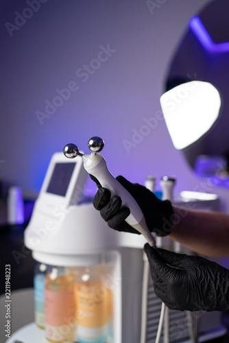 Esthetician holding a microcurrent device with black gloves in a beauty clinic