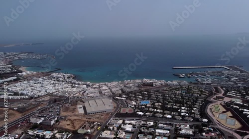 Aerial view of a coastal city with a large body of water urban development and a pier
