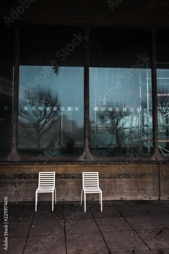 Two white chairs in front of a large glass window in London