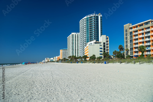 A curved highrise tower dominates the Florida coast beneath a clear sky.