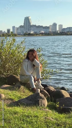 Young Woman In White Sweater Sitting On Rocky Lake Shore Video