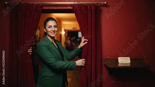An usher opens the red velvet cinema curtain
