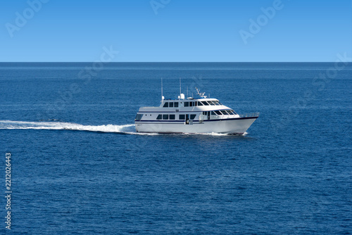 On the open ocean water travels a white passenger ship with windows