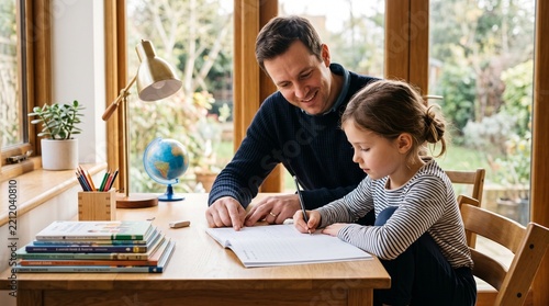 Supportive Father Helping Child Complete Homework at Home Desk
